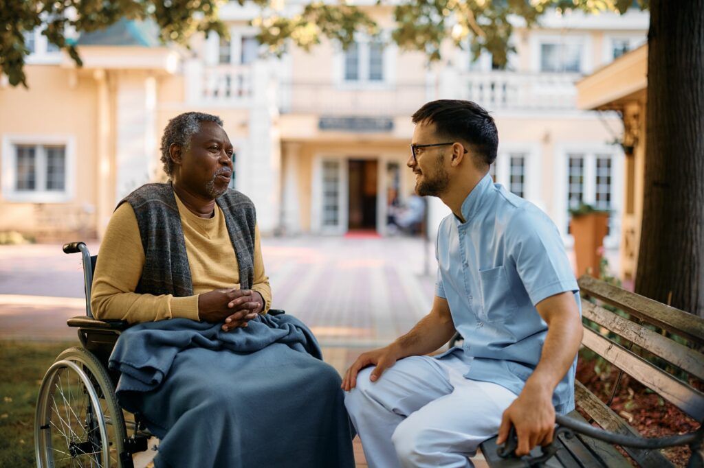 black-senior-in-wheelchair-talking-to-male-nurse